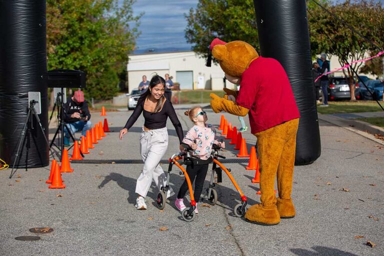 Fezzy talks to a young woman and a child with a walker