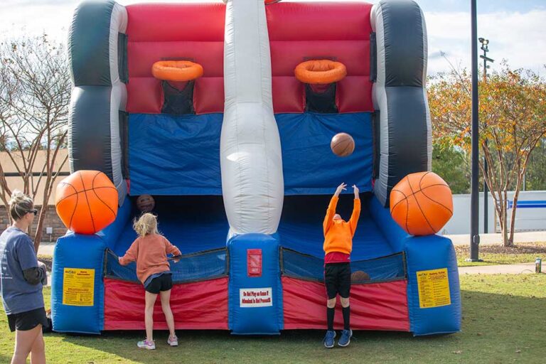 children throw a basketball into an inflatable basketball hoop