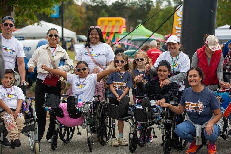 a group of people, including wheelchair users, smile at the camera