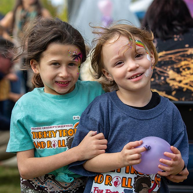 two children with face paint smiling for the camera