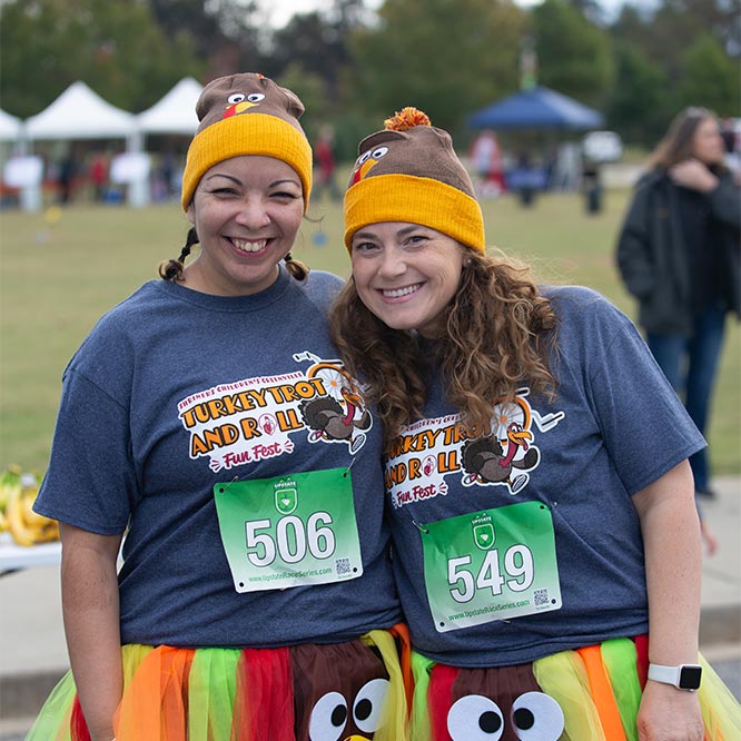 two women in turkey skirts smile at the camera