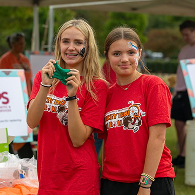 two girls with face paint playing with slime smile at the camera