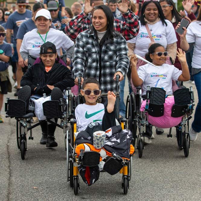 group of people pushing children in wheelchairs