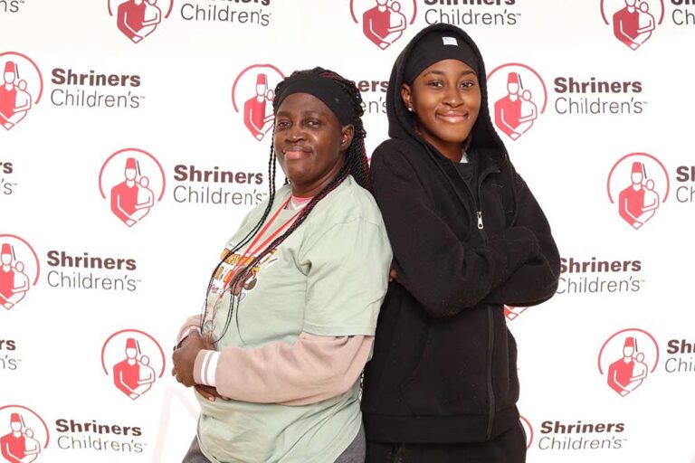 Two women standing back-to-back and smiling